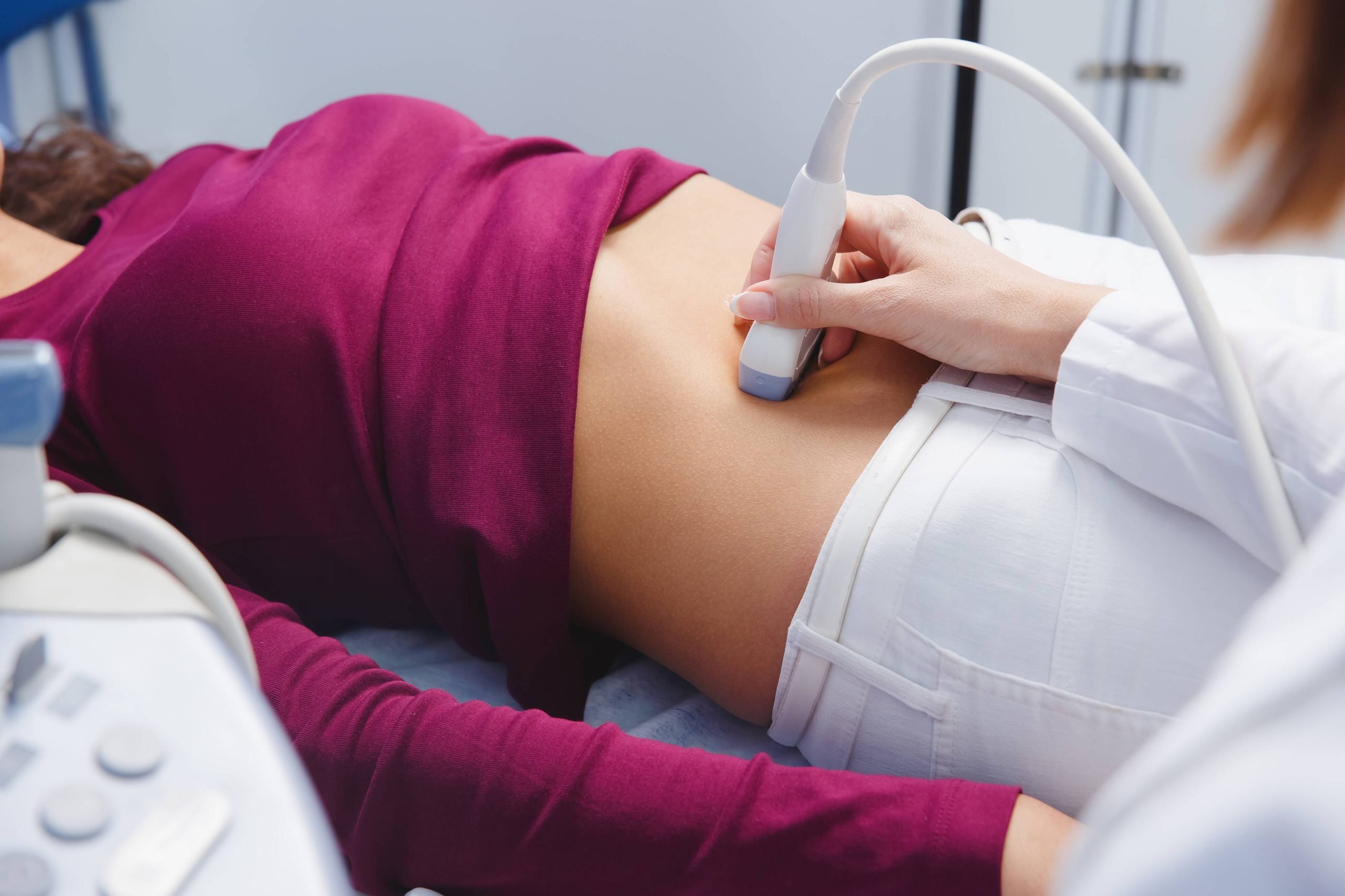 Female doctor operating pelvic ultrasound scan examining pelvis of her female patient